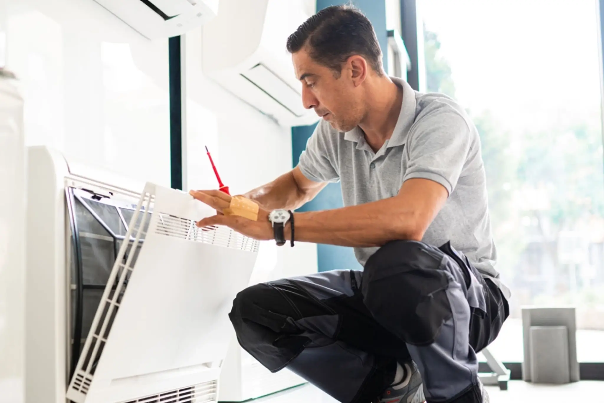 Technician inspecting air conditioning unit indoors.