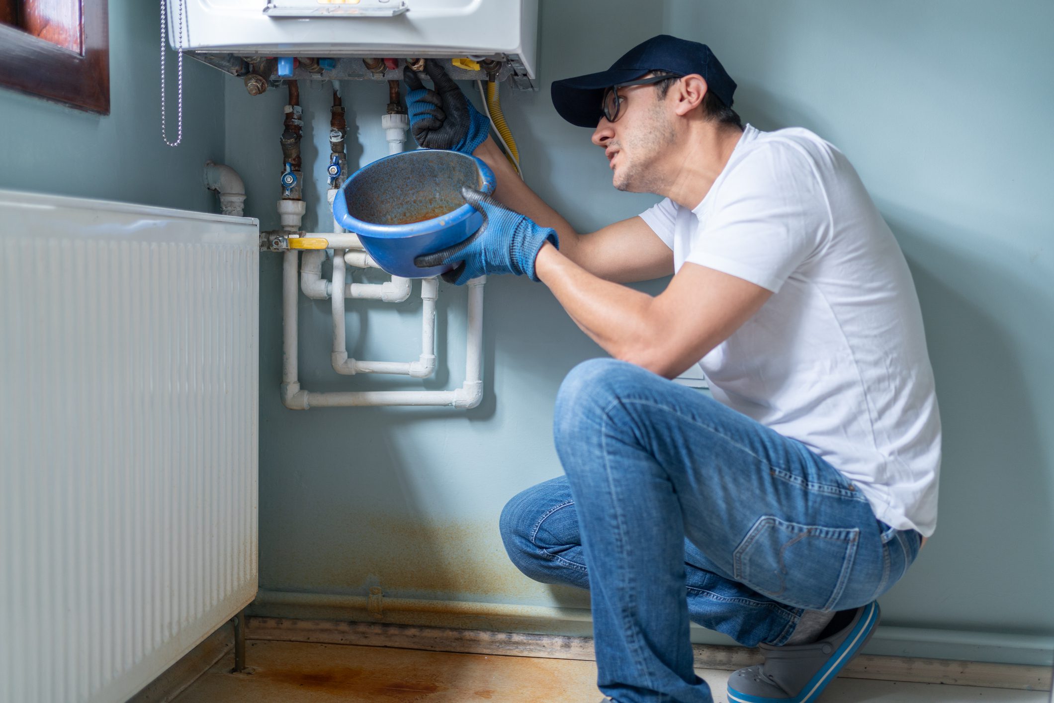 Man Looking At Water Leaking From Broken Natural Gas Combi Boiler