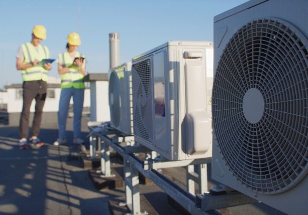 Installation repair and maintenance process of an AC unit fan on top of a building roof. Technicians at work preparing and inspecting the cooling system